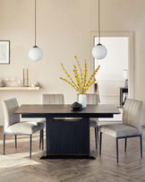 A contemporary dining room set featuring a dark wood rectangular table with a subtly textured surface and fluted side panels, flanked by elegantly curved cream upholstered chairs with slim black metal legs. Two spherical white pendant lights hang above the table, complementing the modern aesthetic.