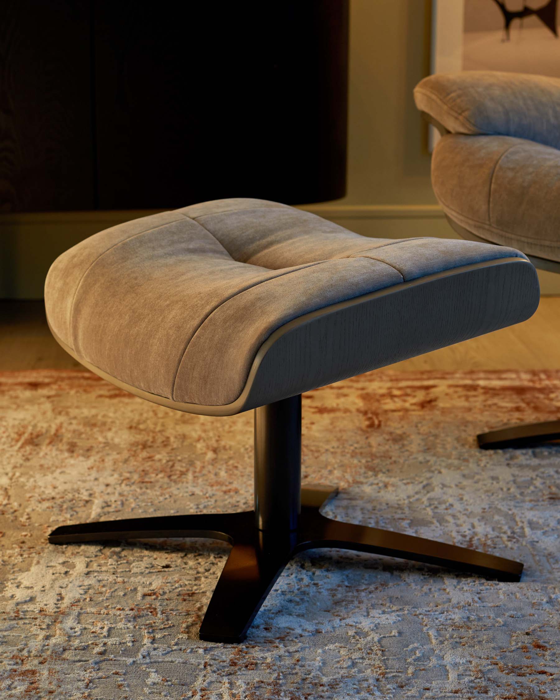 Contemporary grey fabric ottoman with a unique curved design and a sleek, black four-star base.