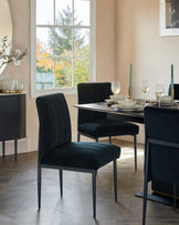 Elegant dining room furniture set featuring a modern rectangular black table and four plush velvet-upholstered chairs with vertical channel stitching and slim black metal legs. A coordinating dark wood sideboard with subtle geometric detailing and metal accents completes the sophisticated ensemble.