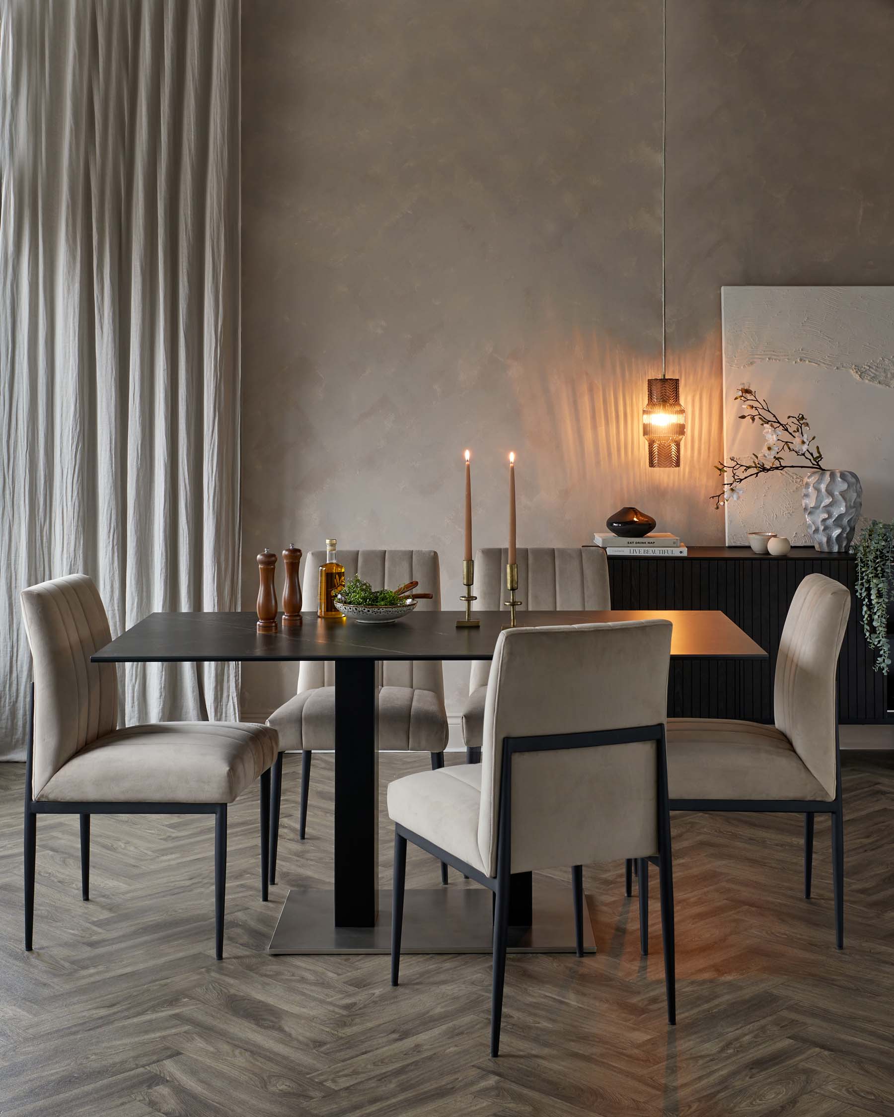 Modern dining set featuring a sleek black table and plush beige chairs with metal frames, accented by candles and decor.