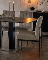 Modern dining table with sleek black metal base and velvet-upholstered chairs featuring vertical tufting in a neutral tone.