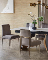 Elegant dining set featuring a sleek marble table and plush velvet chairs with gold accents, complemented by a chic floral centerpiece.