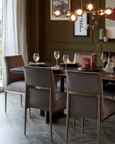 Elegant dining room with a contemporary dark wood round table and four plush upholstered chairs with metal accents, set beneath a stylish modern chandelier with spherical glass shades.