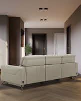 A modern, light-colored leather sofa with sleek lines and metal legs, set in a contemporary interior space.