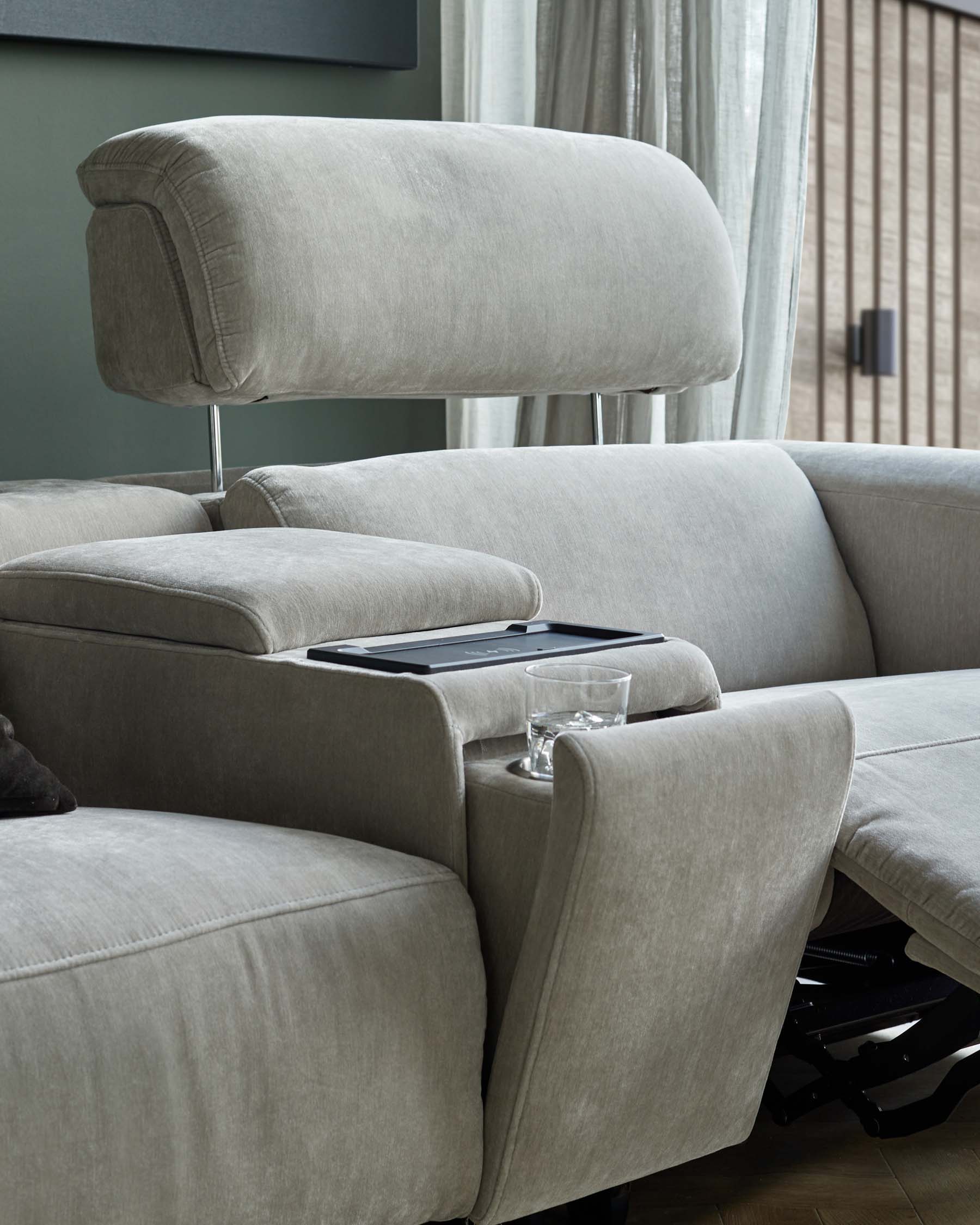 Contemporary grey sofa with plush cushions, adjustable headrest, integrated side table, and glass holder for modern living.