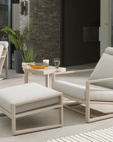 Stylish outdoor furniture set featuring a light gray cushioned armchair, ottoman, and a sleek side table with an amber bowl.