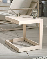 Elegant beige side table with a minimalist design, paired with a glass of water and sunglasses, complements nearby seating.