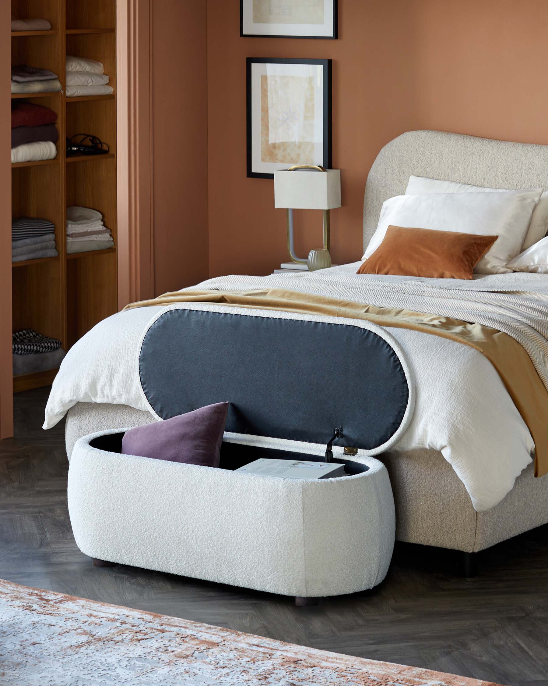 A cozy bedroom featuring a plush bed, a soft storage ottoman with a hidden compartment, and a modern bedside lamp.