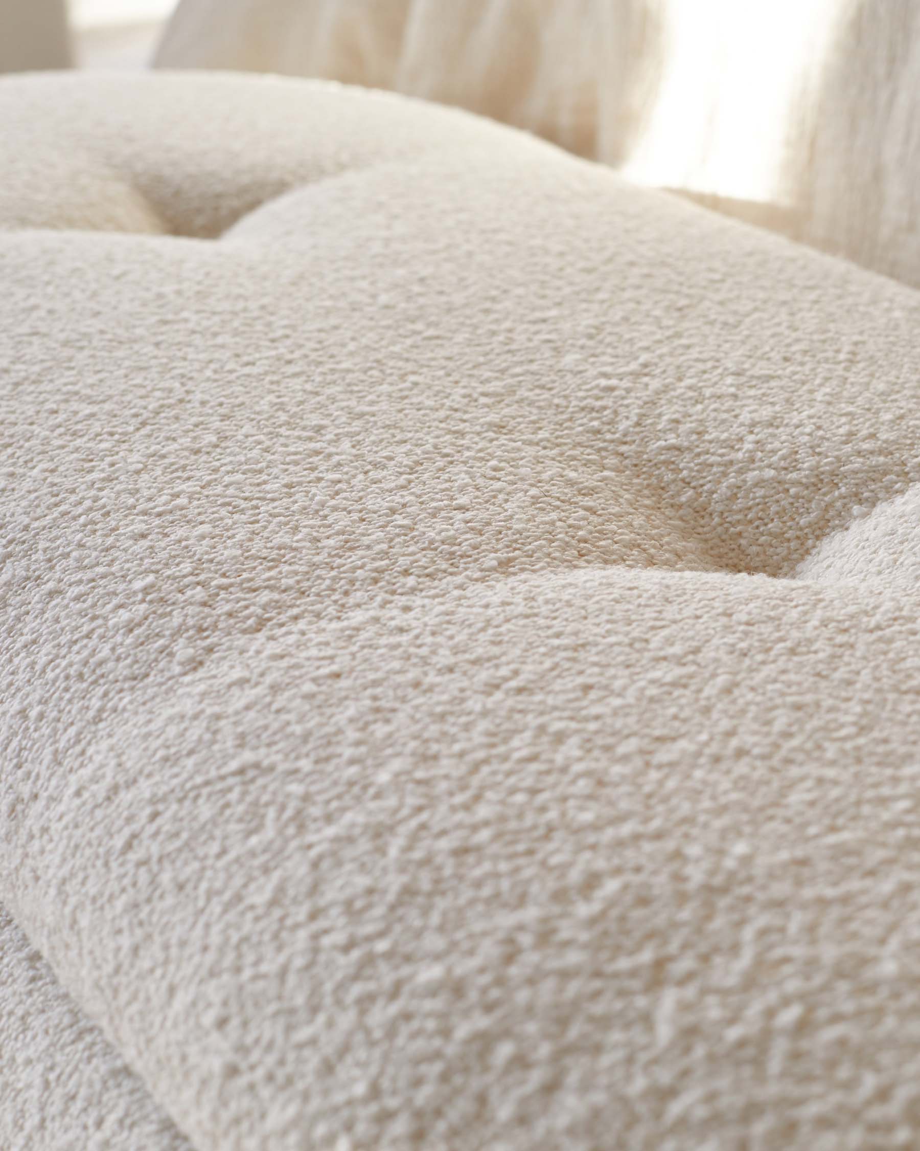 Textured beige upholstery with tufted detailing, offering a soft and inviting look, ideal for modern living spaces.