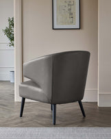 Elegant modern armchair with smooth grey upholstery and four splayed black wooden legs. The chair's design features a slightly curved back with a clean, minimalist silhouette, suitable for contemporary interior spaces.