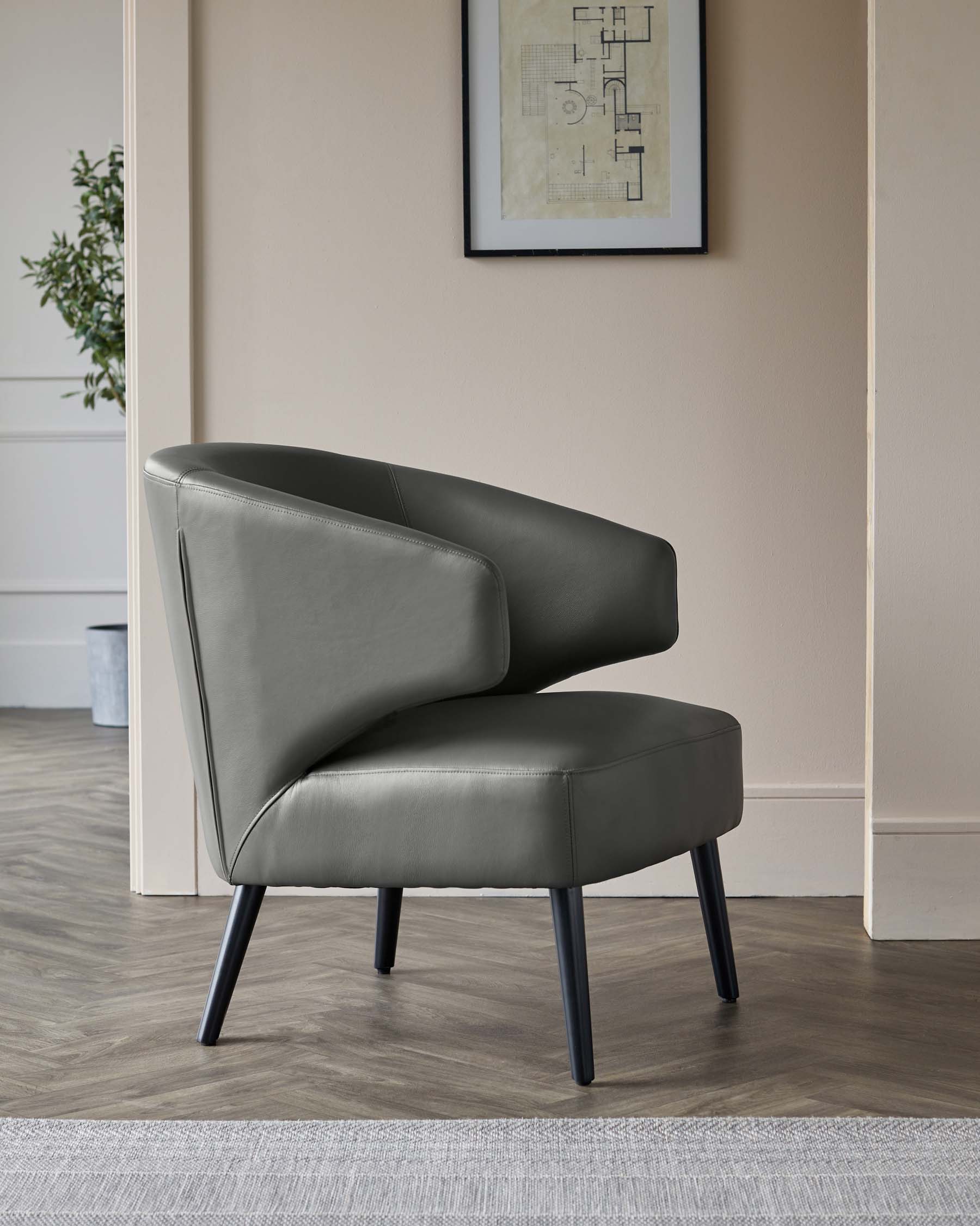 Modern charcoal grey accent chair with sleek lines and angled black wooden legs, situated in a contemporary room setting near a wall art piece and a potted plant.