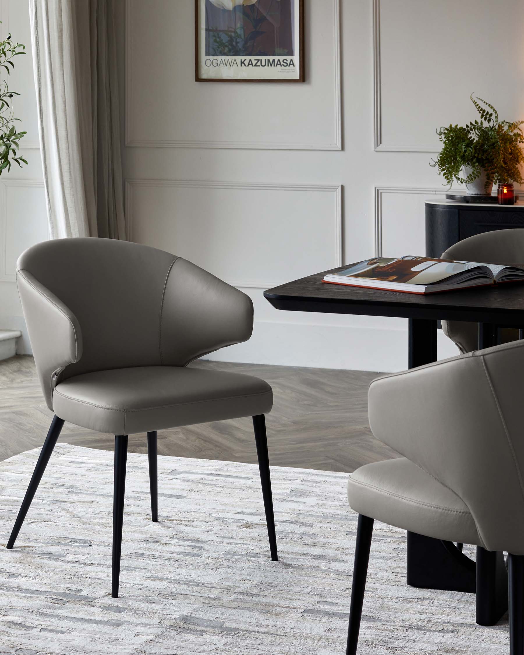 Stylish grey upholstered chairs with sleek black legs are paired with a modern black table, set on a light textured rug.