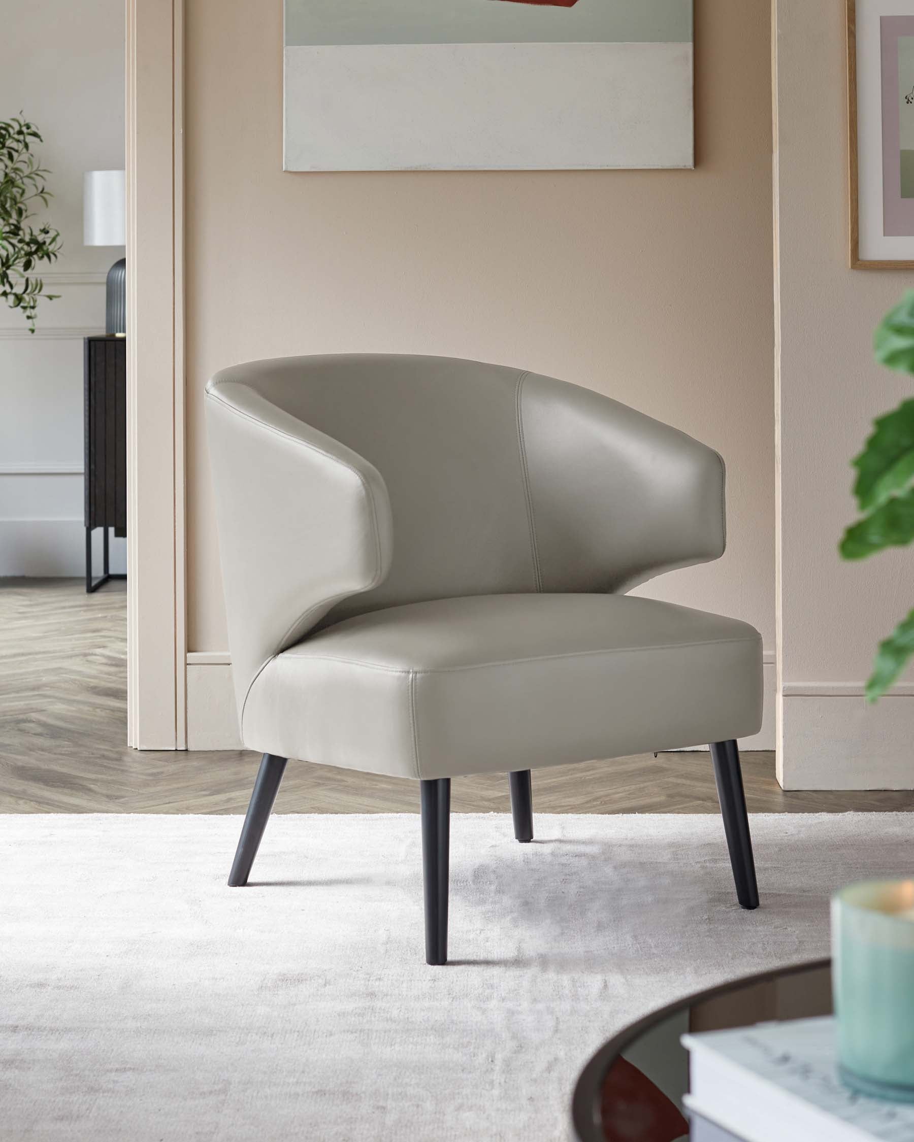 Elegant modern armchair in light grey leather upholstery with curved backrest and sleek black metal legs, positioned on a textured white area rug.