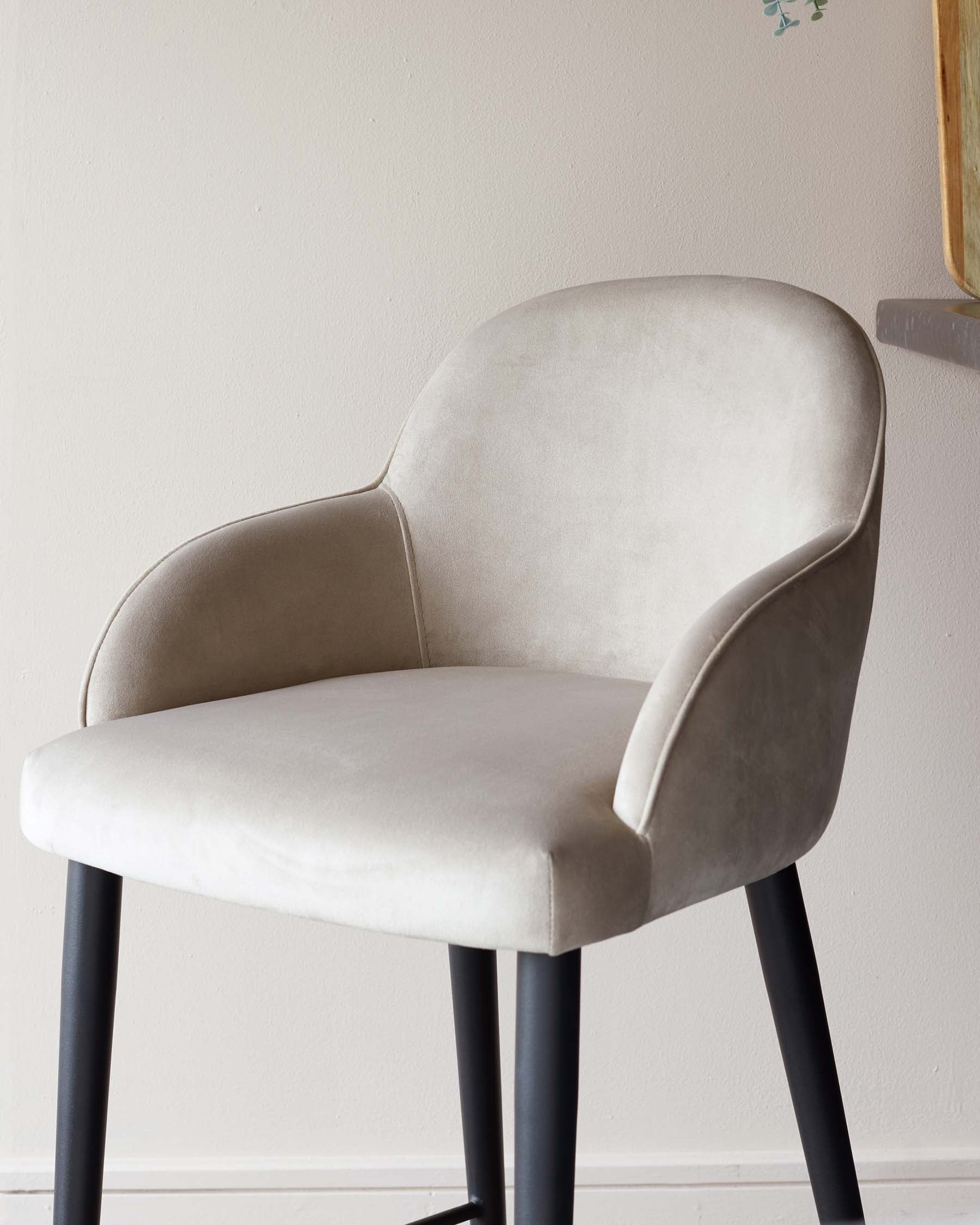 Elegant modern chair with a curved backrest and armrests, upholstered in a light grey fabric. The chair stands on four straight, black metal legs.