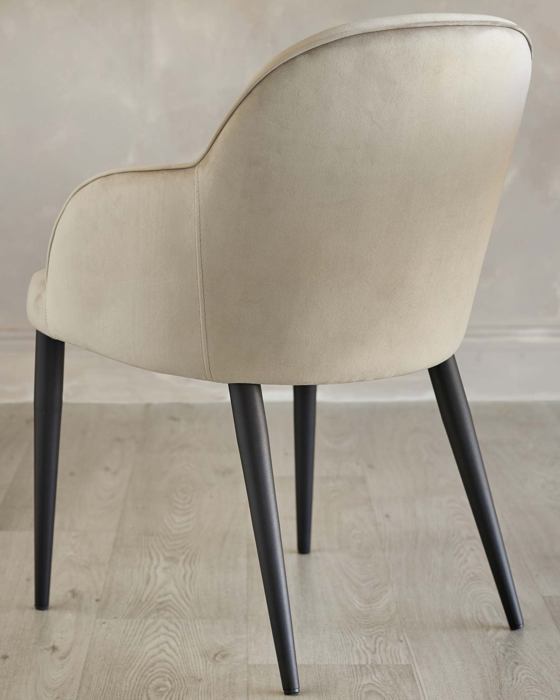 Elegant modern chair with a curved back, upholstered in a light beige fabric, featuring sleek black tapered legs.