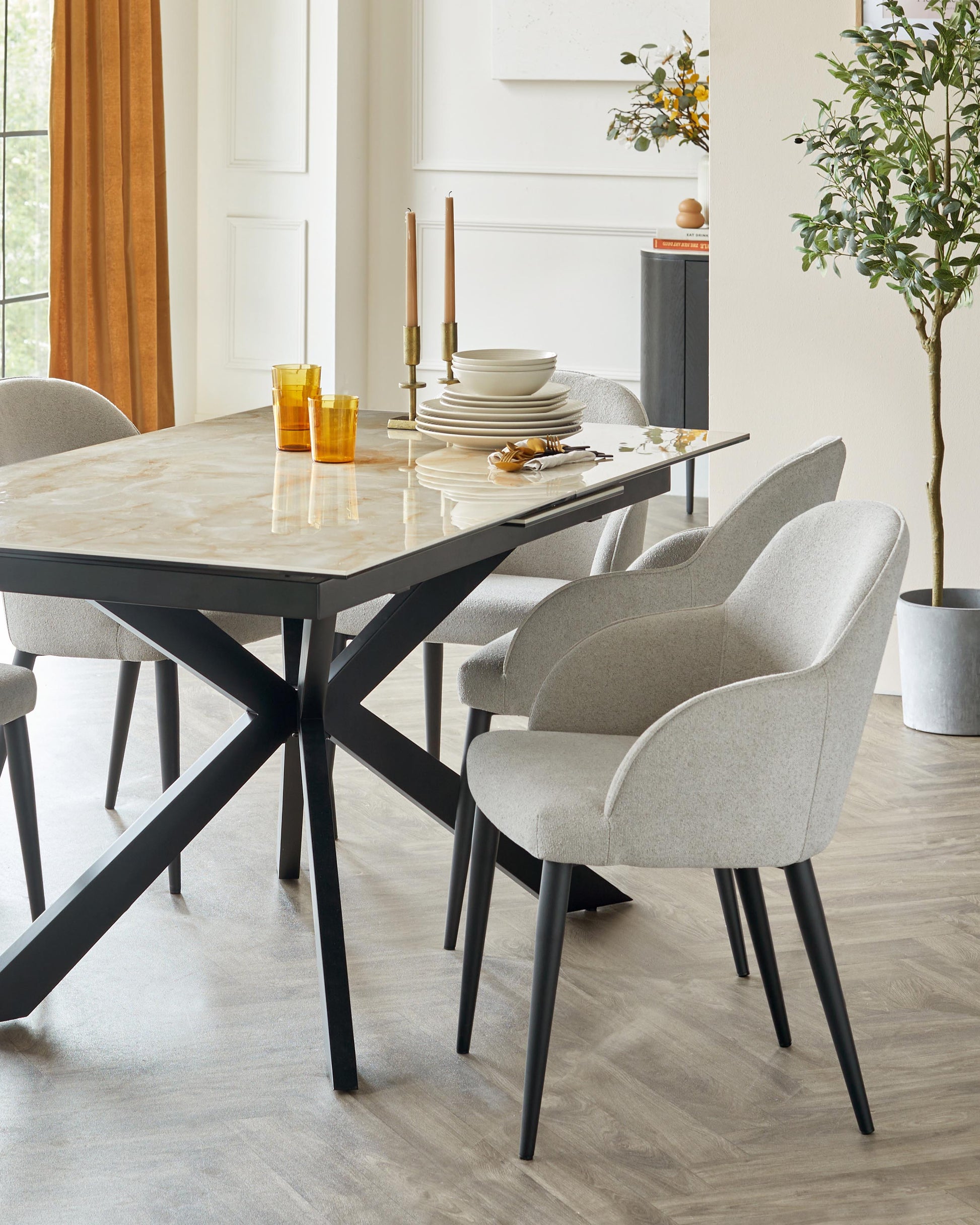 A stylish dining table with a marble top and black base, accompanied by gray upholstered chairs on wooden legs.