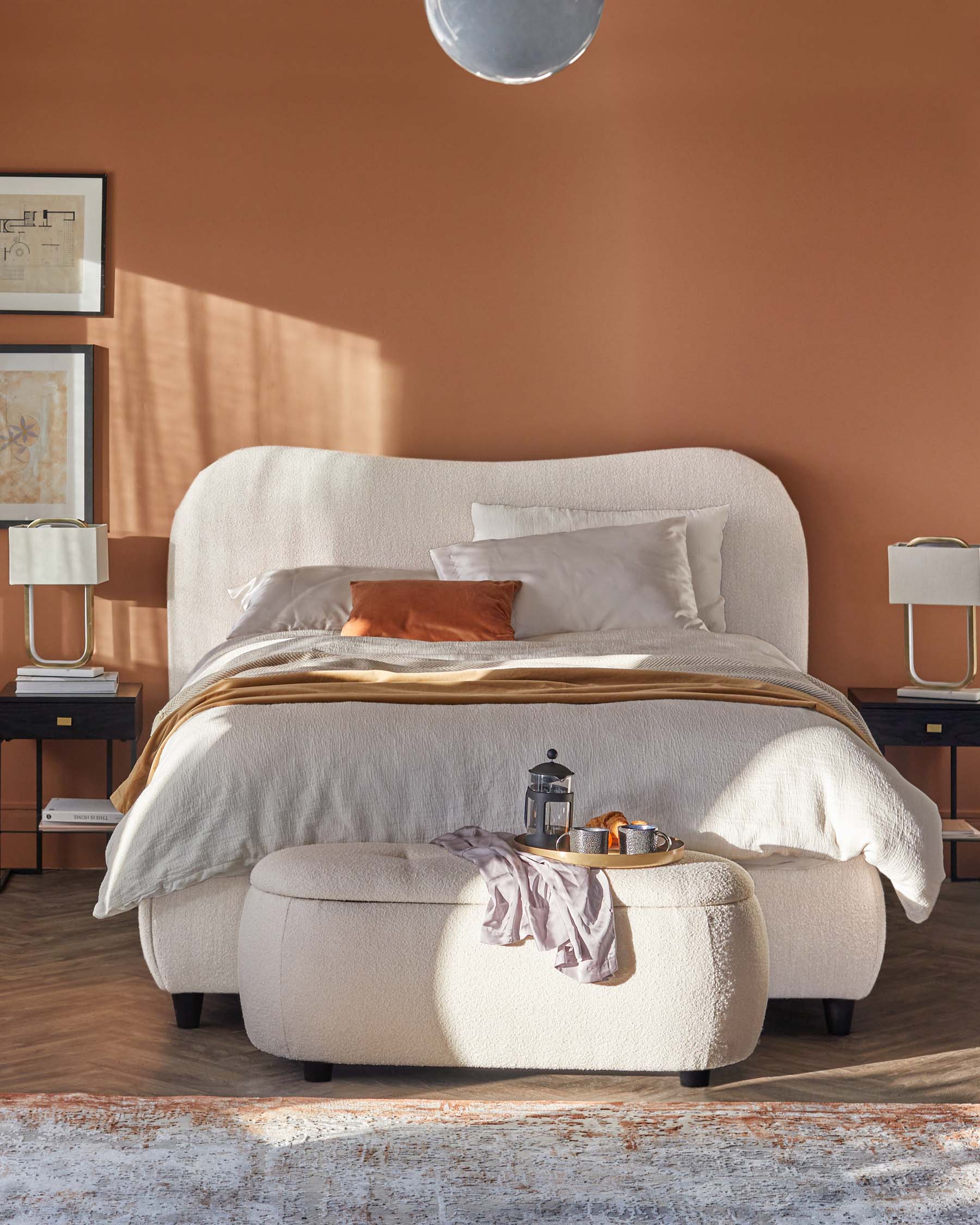 Cozy bedroom featuring a plush, upholstered bed, matching ottoman, side tables with lamps, and layered textiles for warmth.