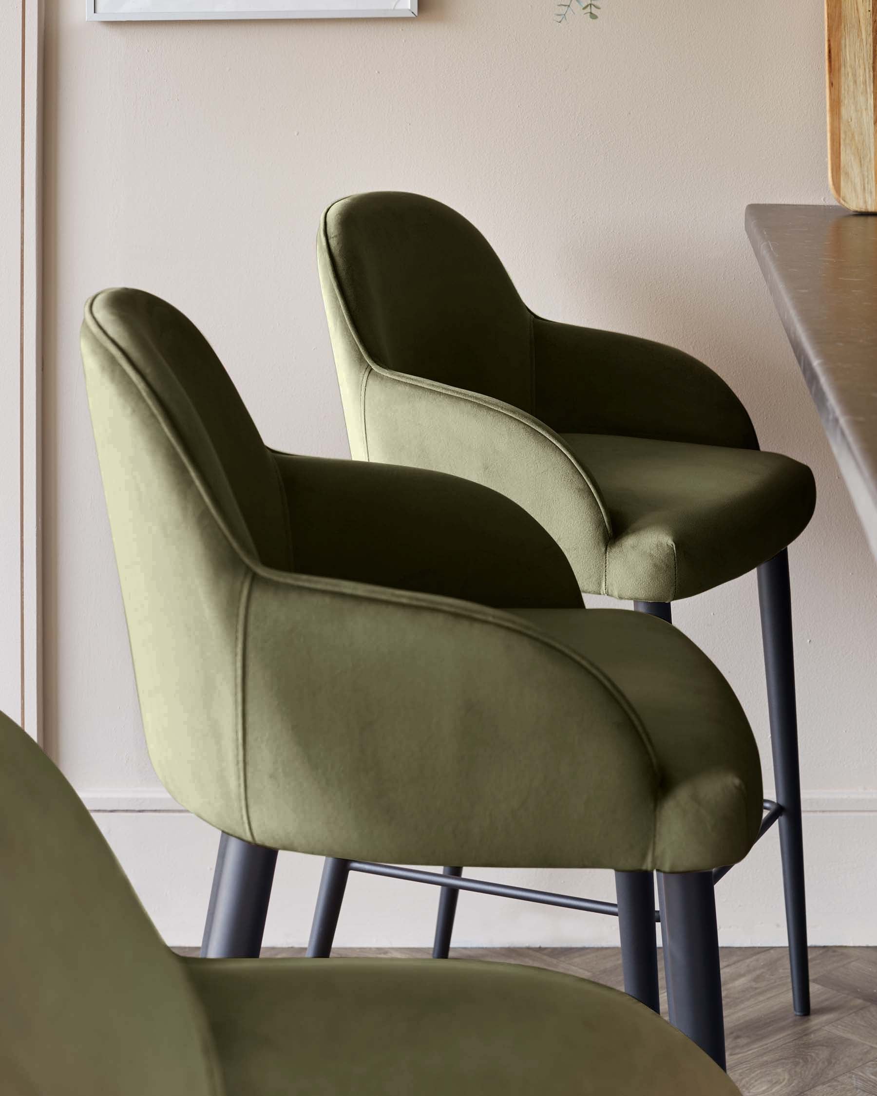 Stylish olive green upholstered chairs with curved backs and black metal legs, perfect for modern dining or bar settings.