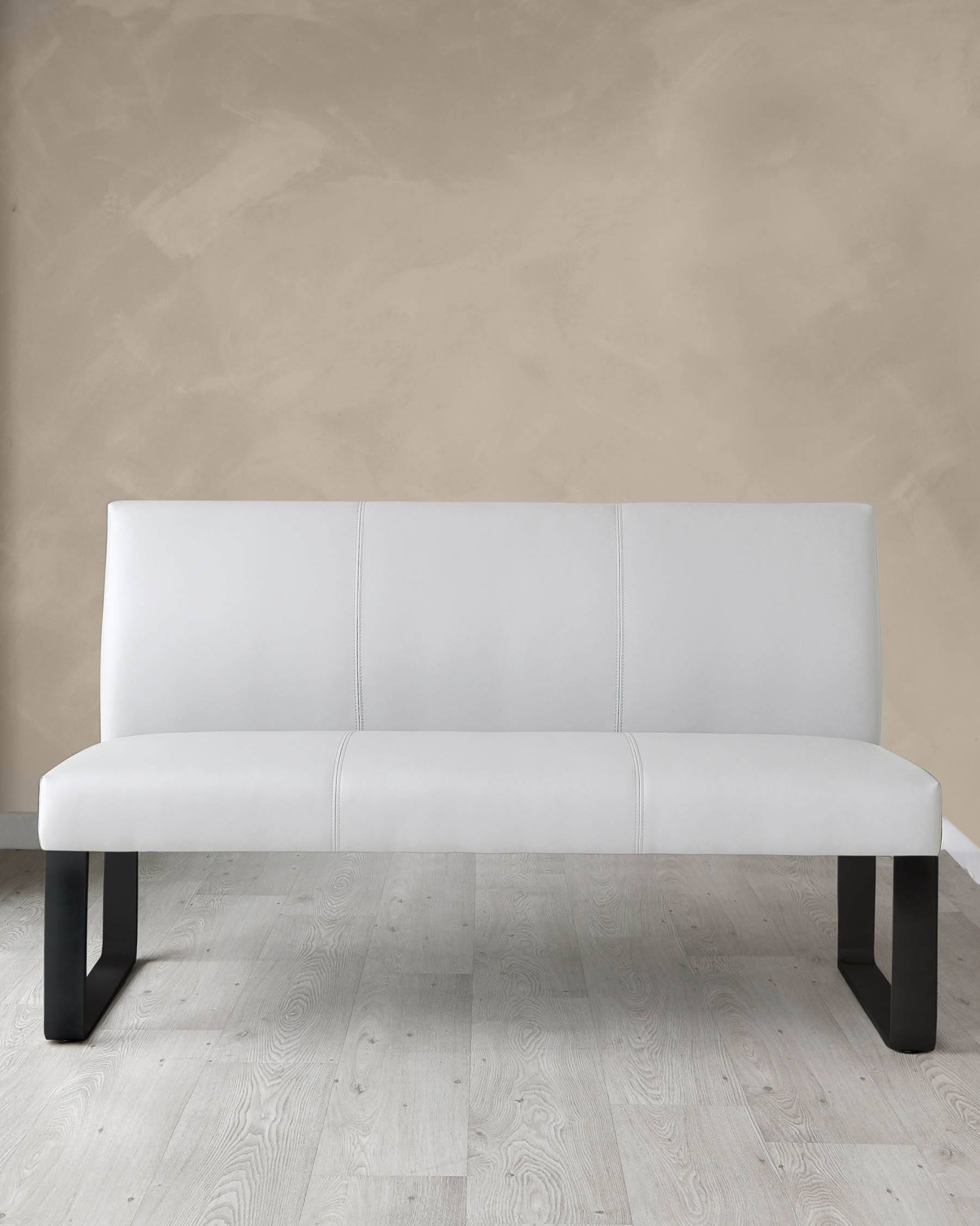 Modern minimalist white leather bench with sleek black legs, presented against a neutral wall on a light wooden floor.