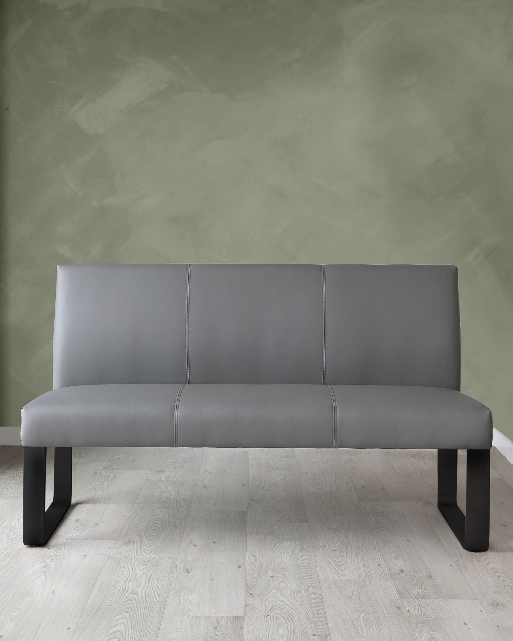 Modern grey upholstered bench with a minimalist design and black legs, positioned against a green textured wall on a light hardwood floor.