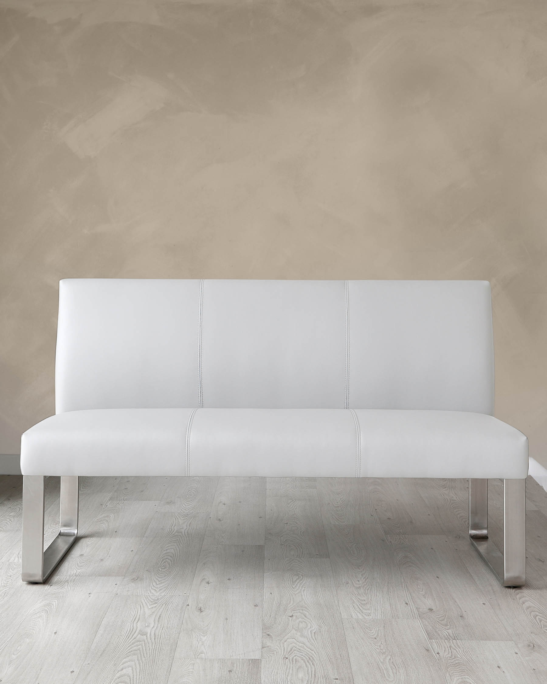 Modern white leather sofa with sleek metal legs against a neutral wall and light wooden floor.