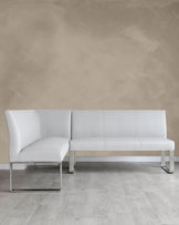 Modern white leather sectional sofa with clean lines and chrome metal legs, featuring a chaise lounge on one end.