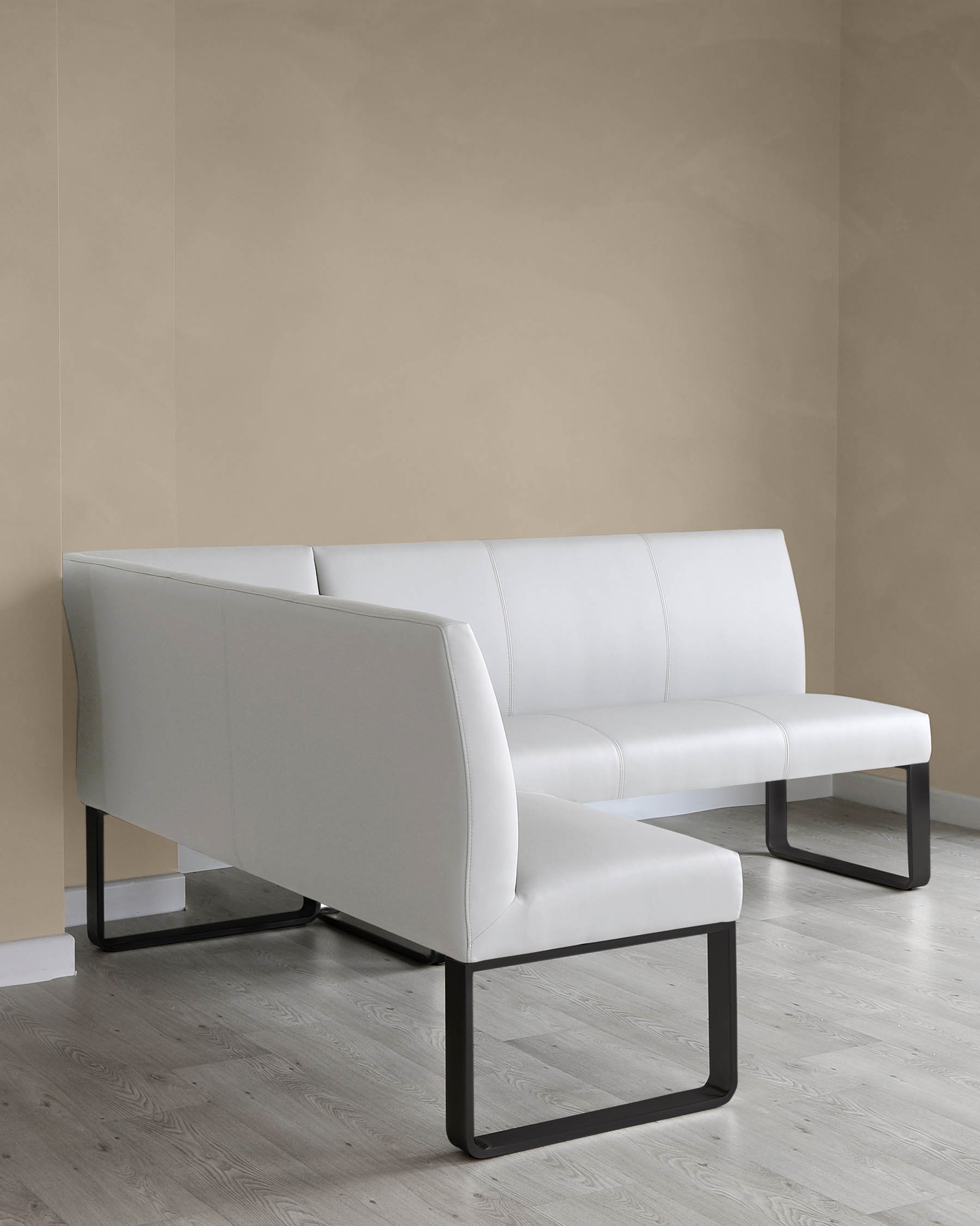 Modern minimalist style sofa with a clean white upholstery and a sleek black metal frame against a neutral beige wall on a light herringbone patterned floor.