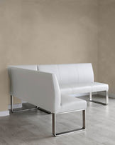 Modern white leather sofa with clean lines and metallic, square-frame legs set against a neutral wall on a light hardwood floor.