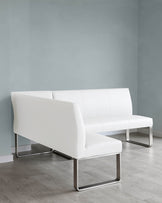 Modern white leather sofa with sleek chrome legs and minimalist design set against a soft blue-grey wall on a light wooden floor.