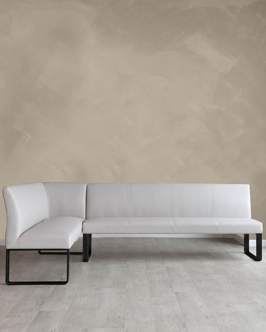 Modern white sectional sofa with clean lines and metal frame legs placed on a light wooden floor against a textured beige wall.