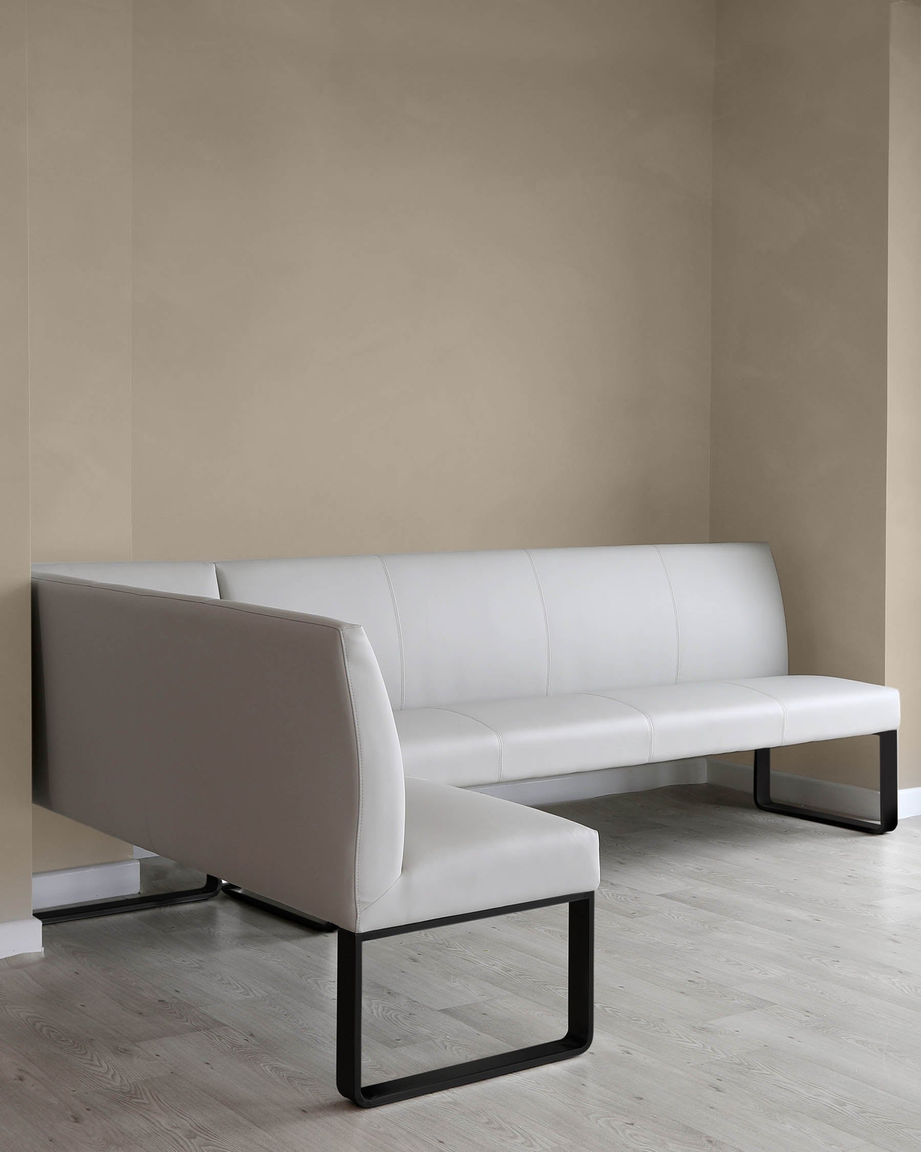 Modern minimalist white leather sofa with black metal frame support sitting on light wood flooring against a two-tone beige wall.