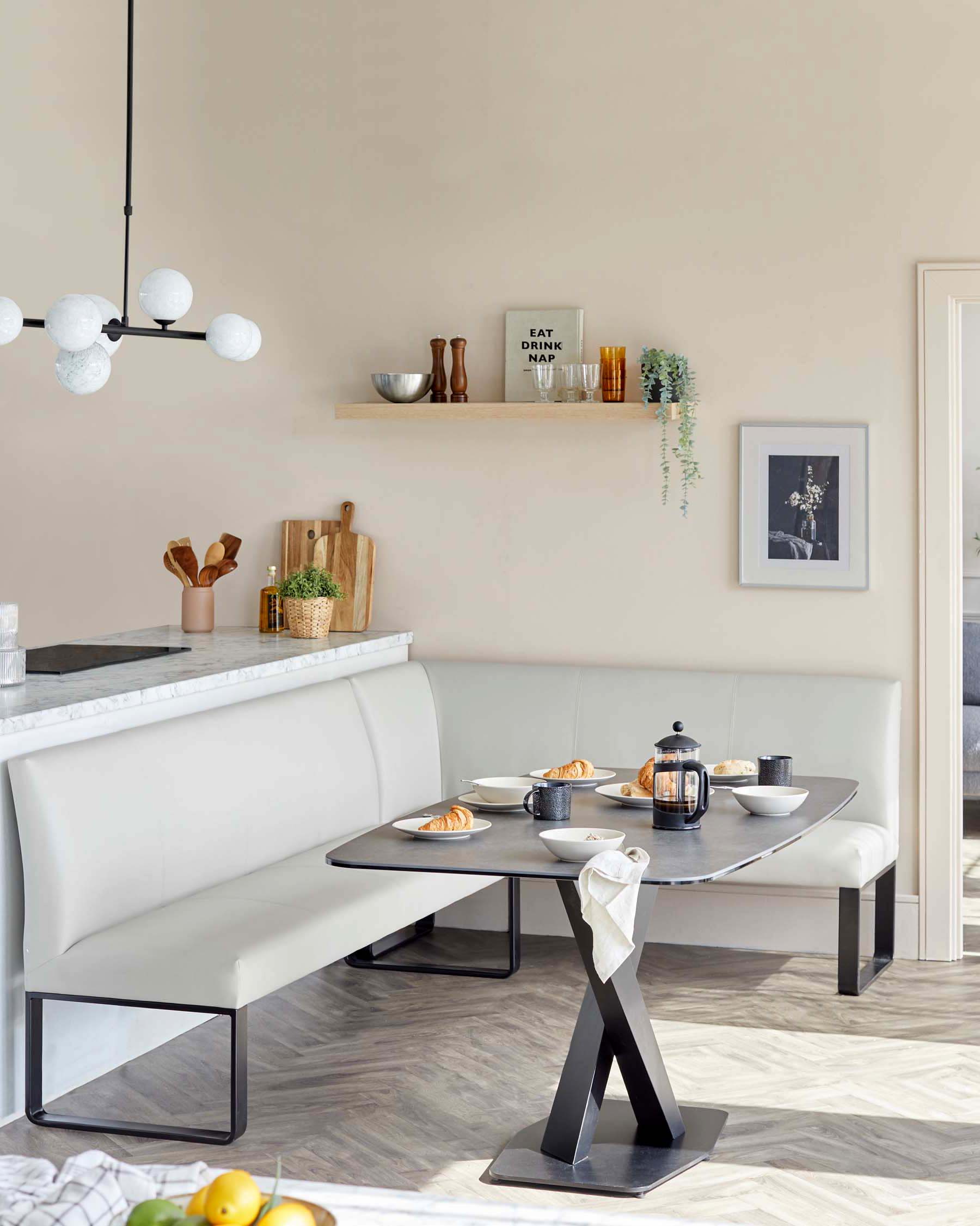 Modern dining furniture featuring a sleek, white upholstered bench with a high back, paired with a contemporary black dining table with a unique geometric base design. The table is rectangular with rounded corners and a dark, possibly marble, tabletop surface.