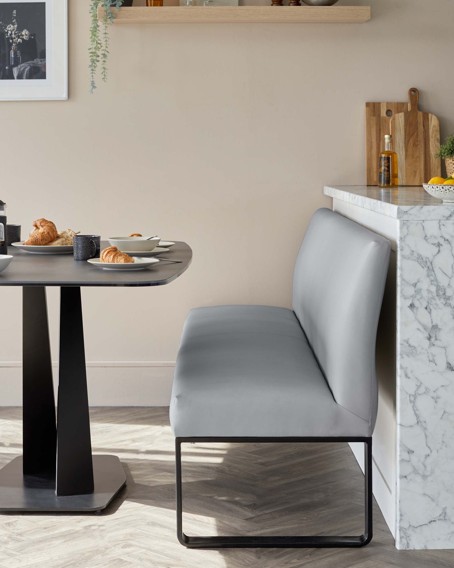 Modern round dining table with a black pedestal base and coordinated elegant grey upholstered dining chair with a minimalist black metal frame.