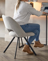 Modern minimalist desk chair with light grey upholstery and angled black metal legs.