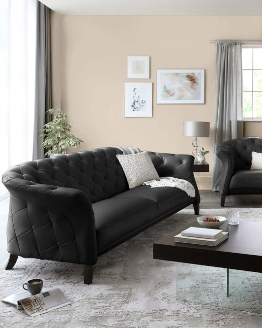 Elegant black tufted sofa with a cozy white throw, paired with a stylish coffee table and chic decor in a modern living space.