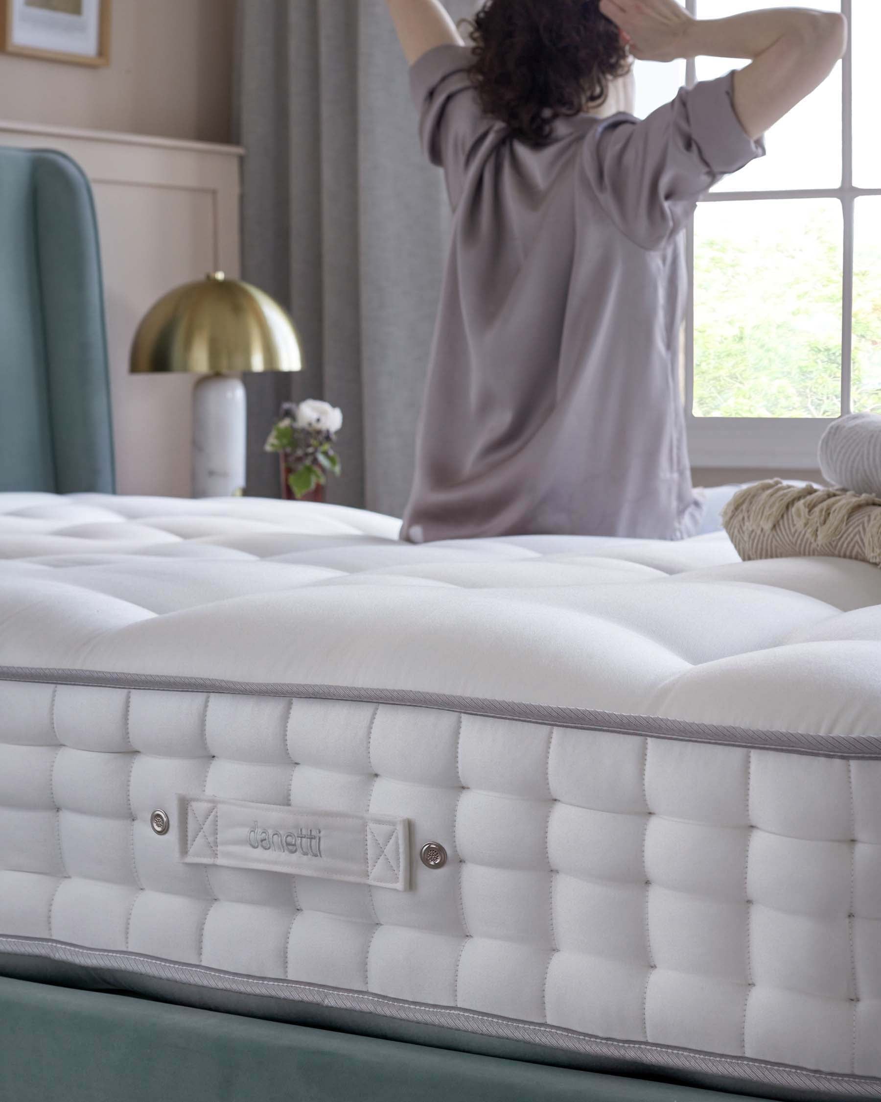 Luxurious mattress with a plush, tufted surface, complemented by a stylish green bed frame and a modern gold lamp.