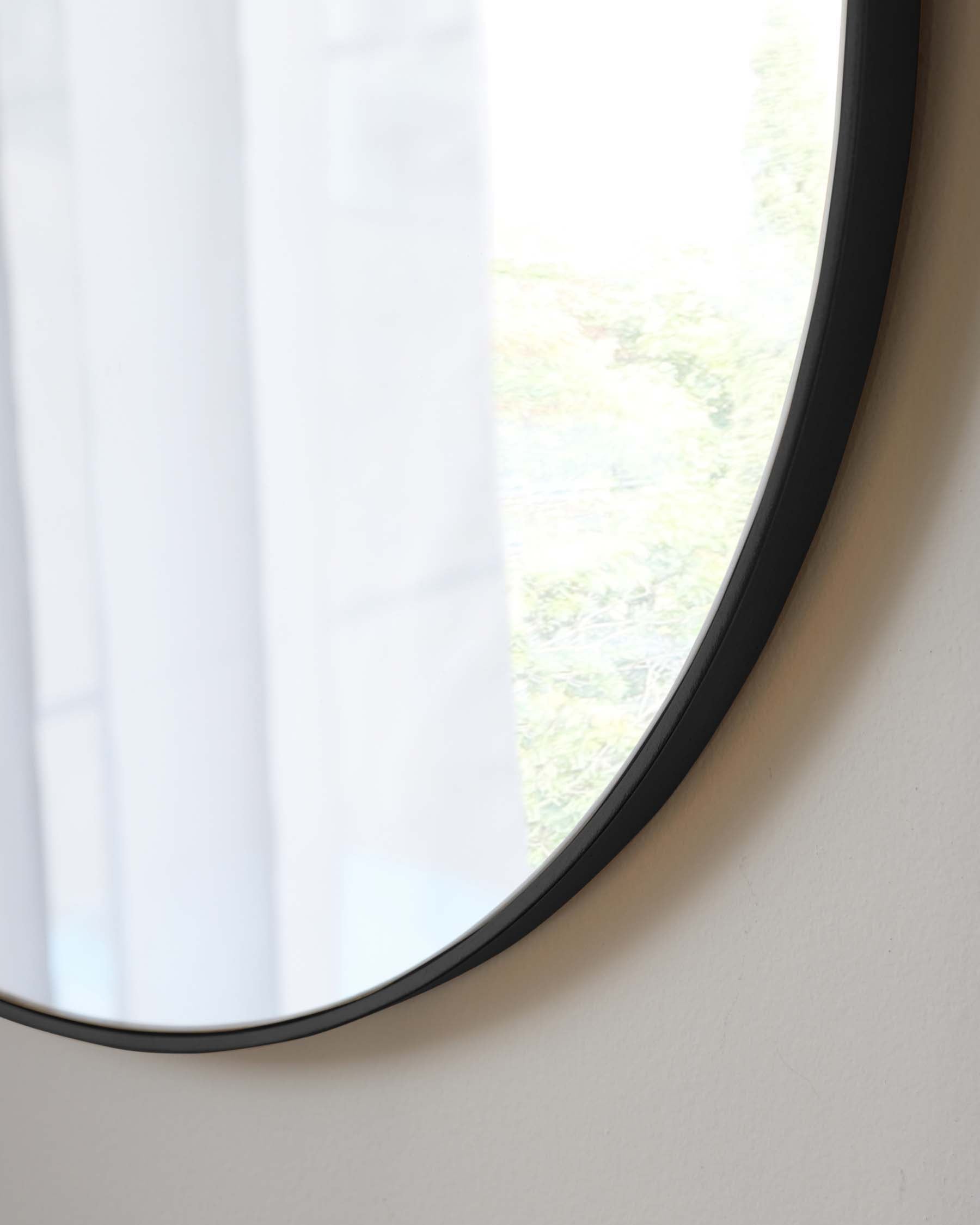 Round wall mirror with a simple black frame.