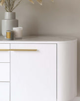 Elegant white curved sideboard with minimalist design, featuring sleek golden handles on its drawers and doors.