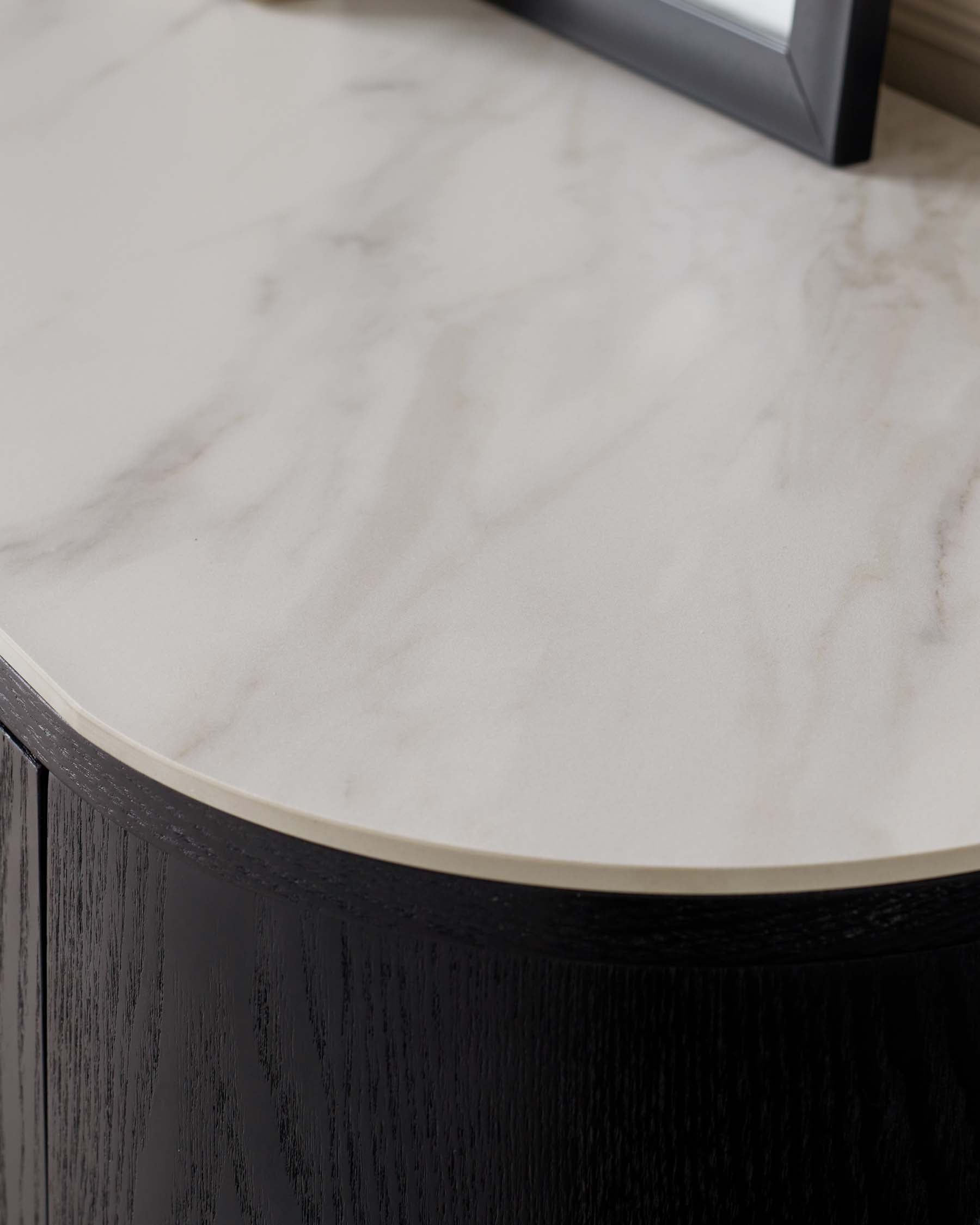 Elegant round table with a marble top displaying subtle white and grey veining and a robust dark wooden body with visible wood grain textures, possibly oak or walnut. The table is designed with a smooth, curved edge, giving it a sleek and modern appearance.