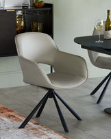 A modern dining chair with a curved cream seat and black metal star base, set against a stylish, light background.