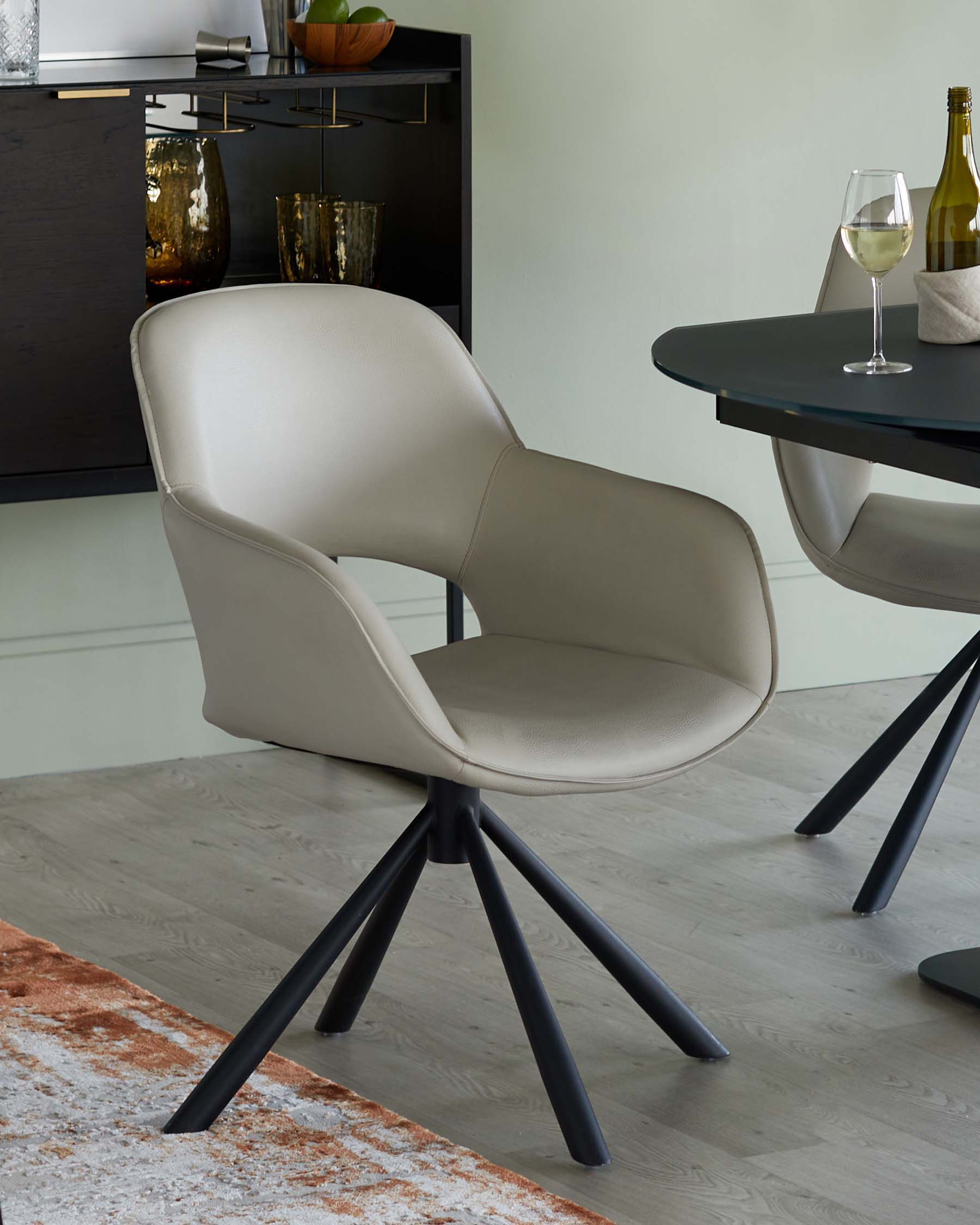 A stylish, modern beige armchair with a comfortable design and sleek black tripod legs, perfect for dining areas.