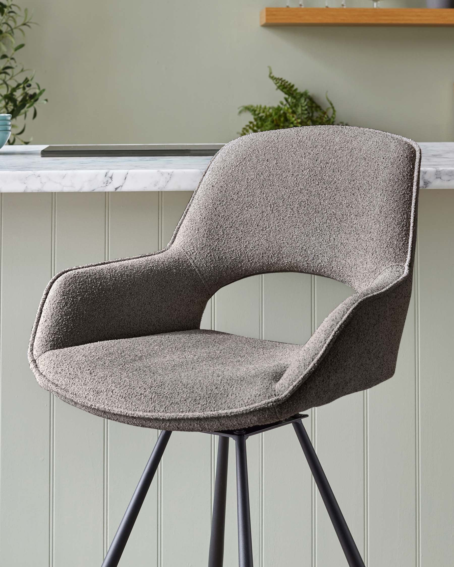 Modern mid-century inspired bar stool with a curved backrest and seat upholstered in textured grey fabric, mounted on a sleek black four-legged metal base with slender angled legs.