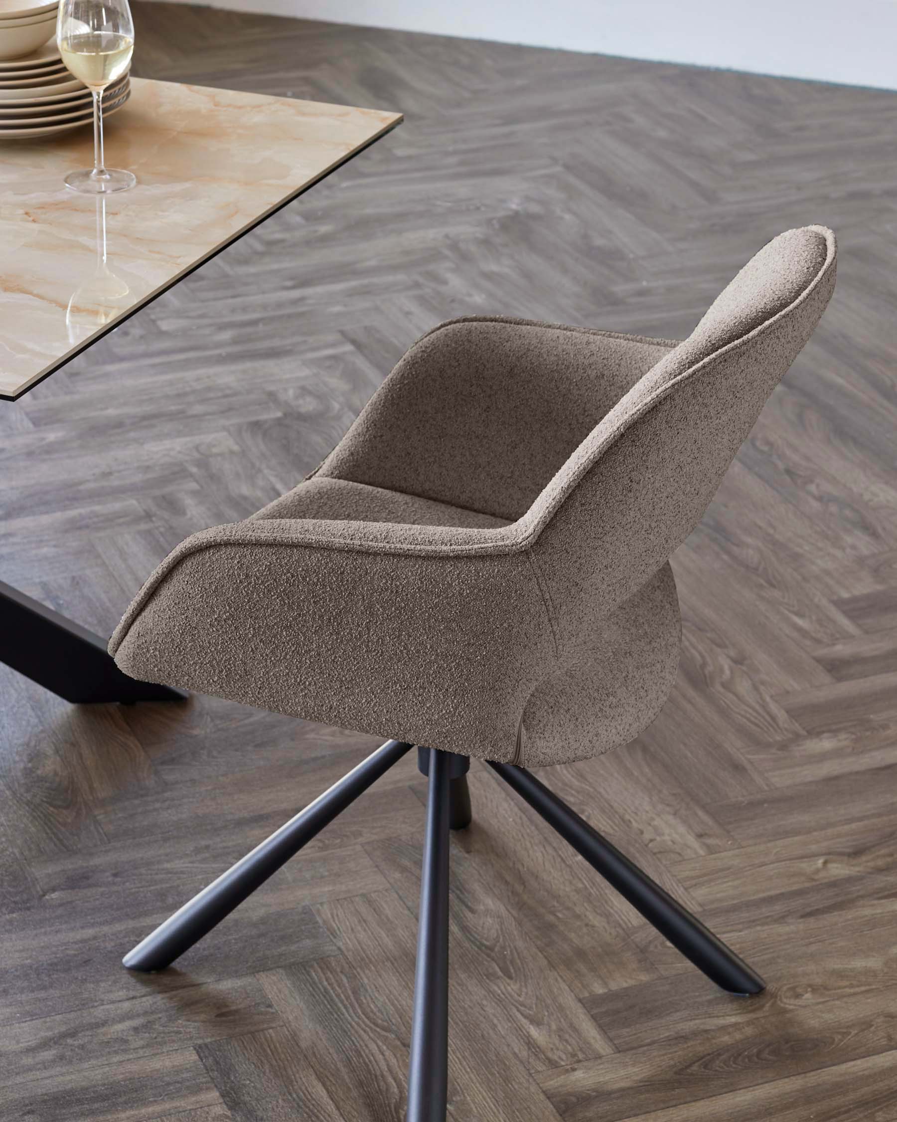 Modern upholstered dining chair with a textured fabric finish in neutral colour and supportive armrests, featuring a sleek four-legged metal base in a matte finish.