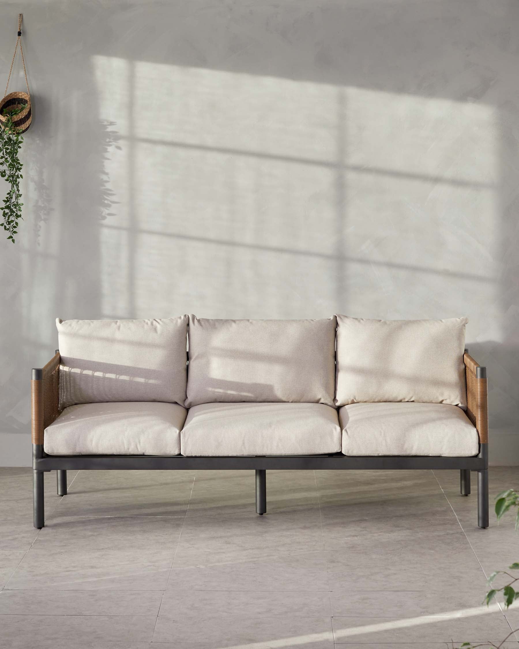 Modern three-seater sofa with a minimalist black metal frame, wooden armrests, and plush beige cushions, displayed in a bright room with soft lighting and a hanging plant.