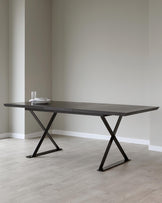 Sleek rectangular dining table with a dark wood top and angular black metal legs, set against a minimalist backdrop.