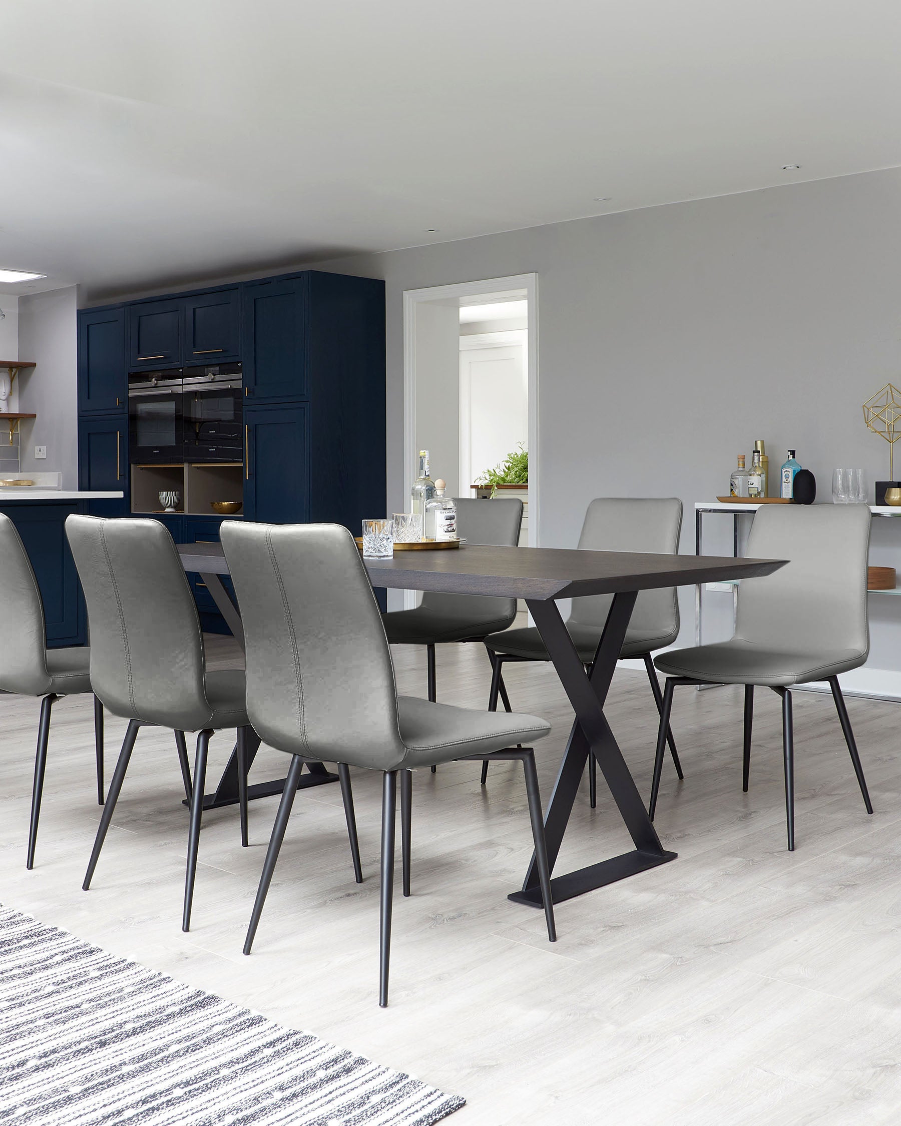 Modern dining set featuring a sleek wooden table with an X-shaped base and six gray upholstered chairs with metal legs.