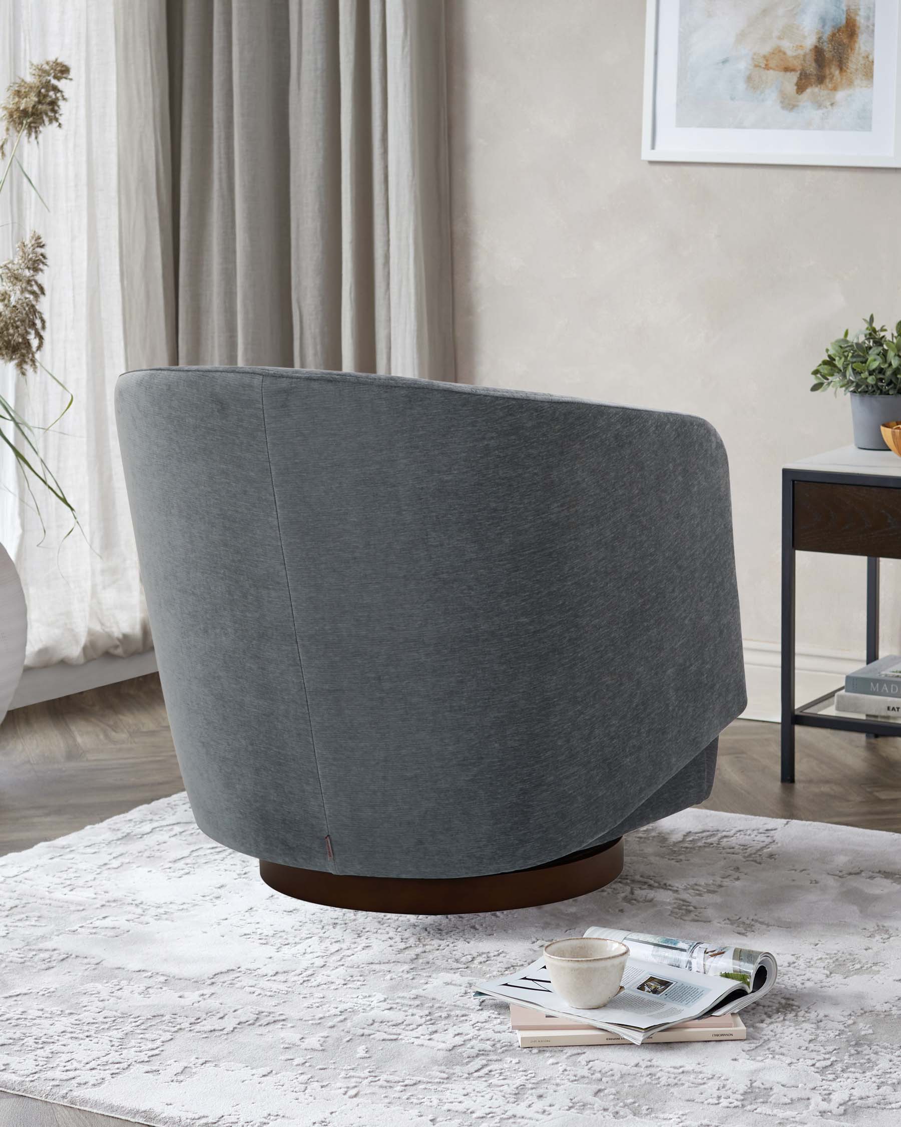 A plush, circular gray chair with a wooden base, placed on a textured white rug, accompanied by a small side table and decor.