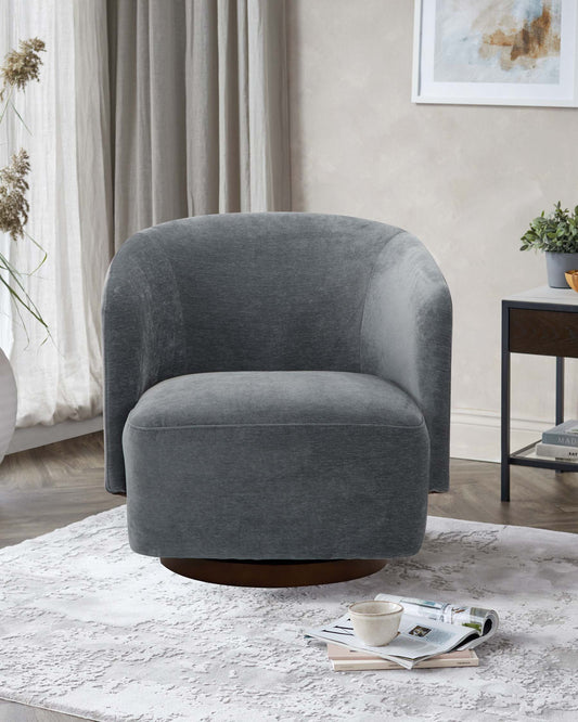 A modern, plush gray swivel chair sits on a textured white rug, complemented by a small side table with magazines and a cup.