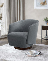 A modern, plush gray swivel chair with a rounded back, sitting on a wooden base, surrounded by a cozy rug and decor.