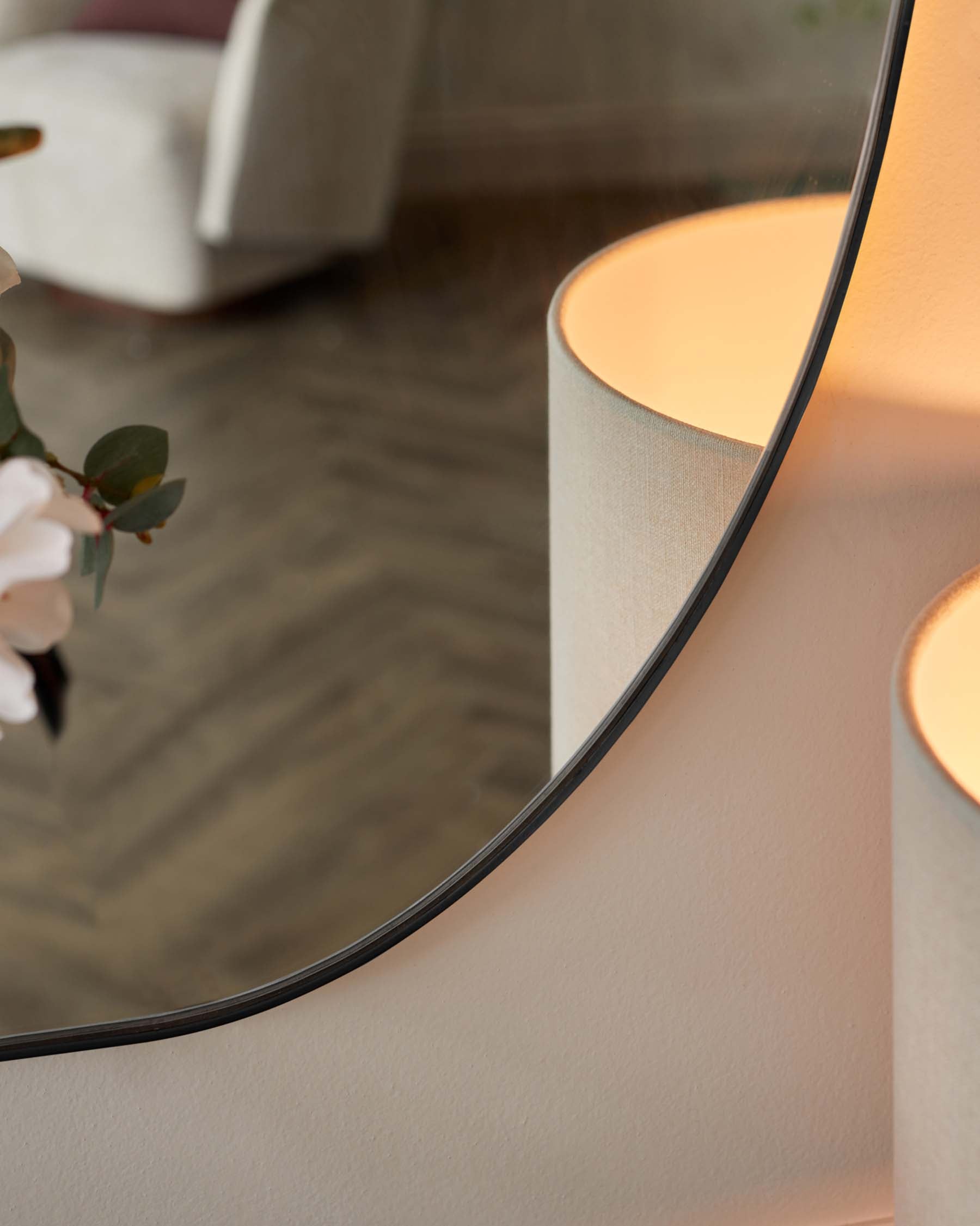 Contemporary round pedestal side table in a soft beige finish, with a reflective round tabletop mirror, featuring a minimalist aesthetic.